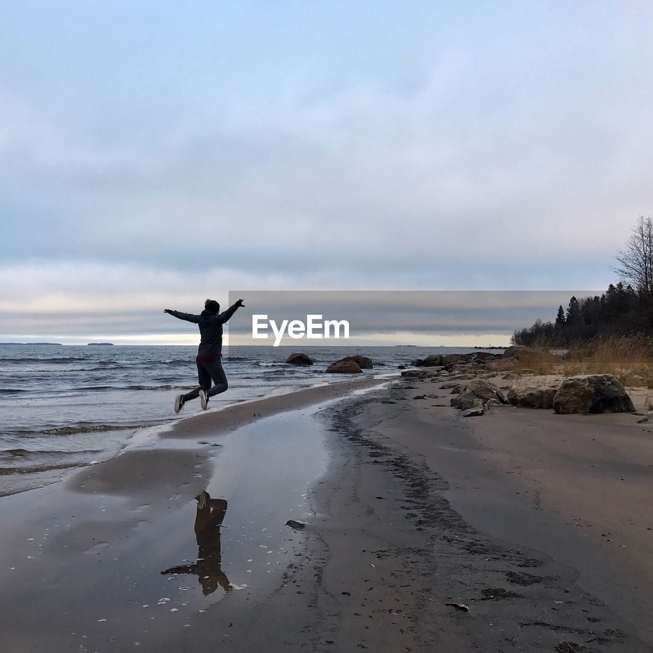 Man jumping on shore against sea at beach