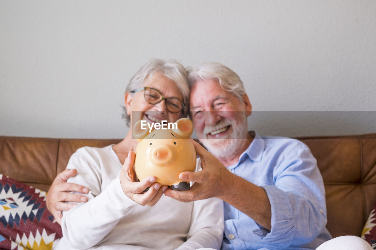 Smiling senior couple holding piggy bank