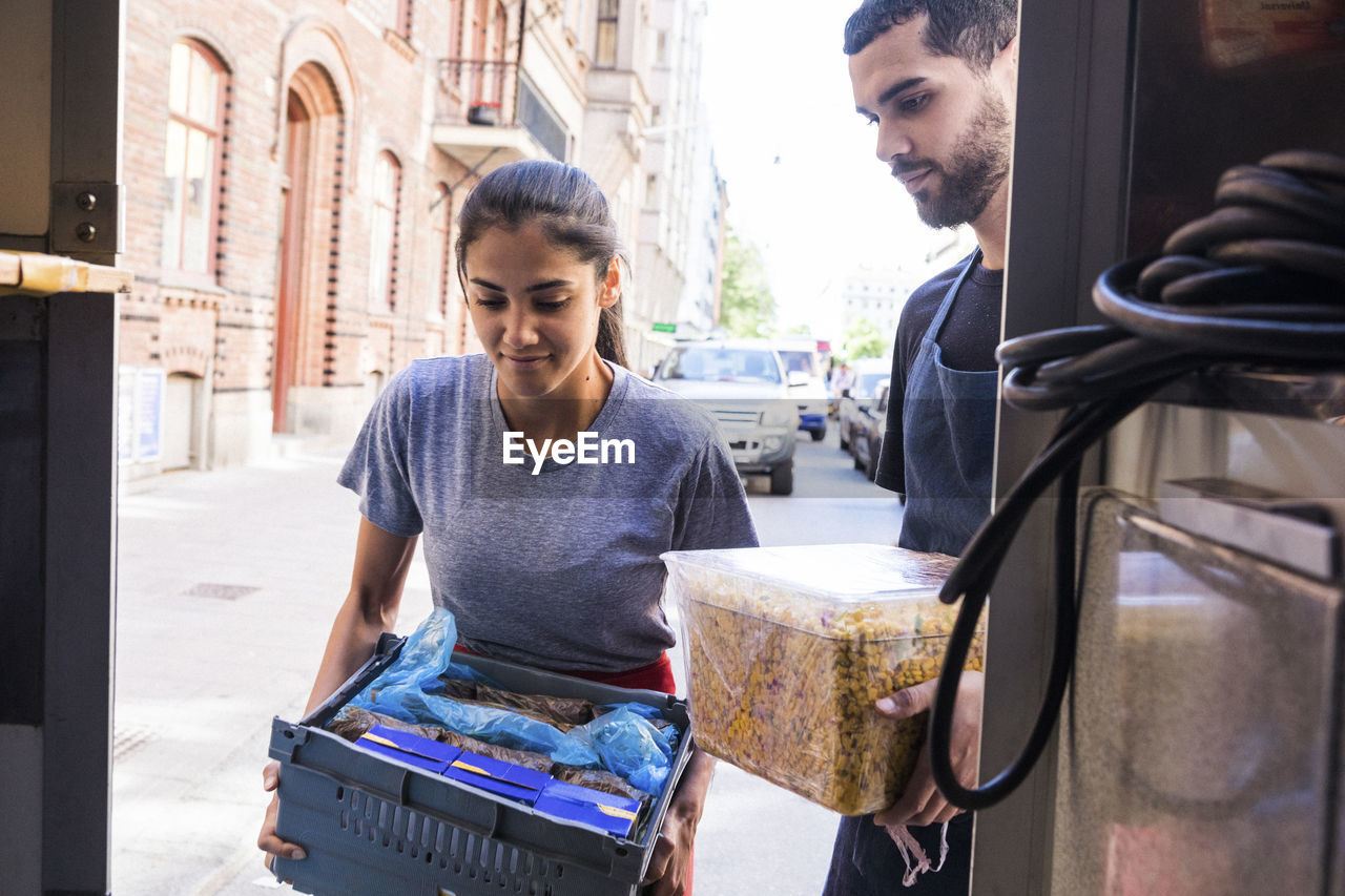 Young multi-ethnic owners carrying food at truck in city