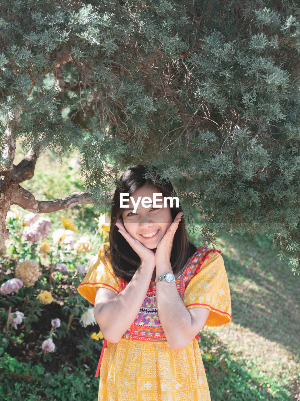 Portrait of smiling young woman standing against trees