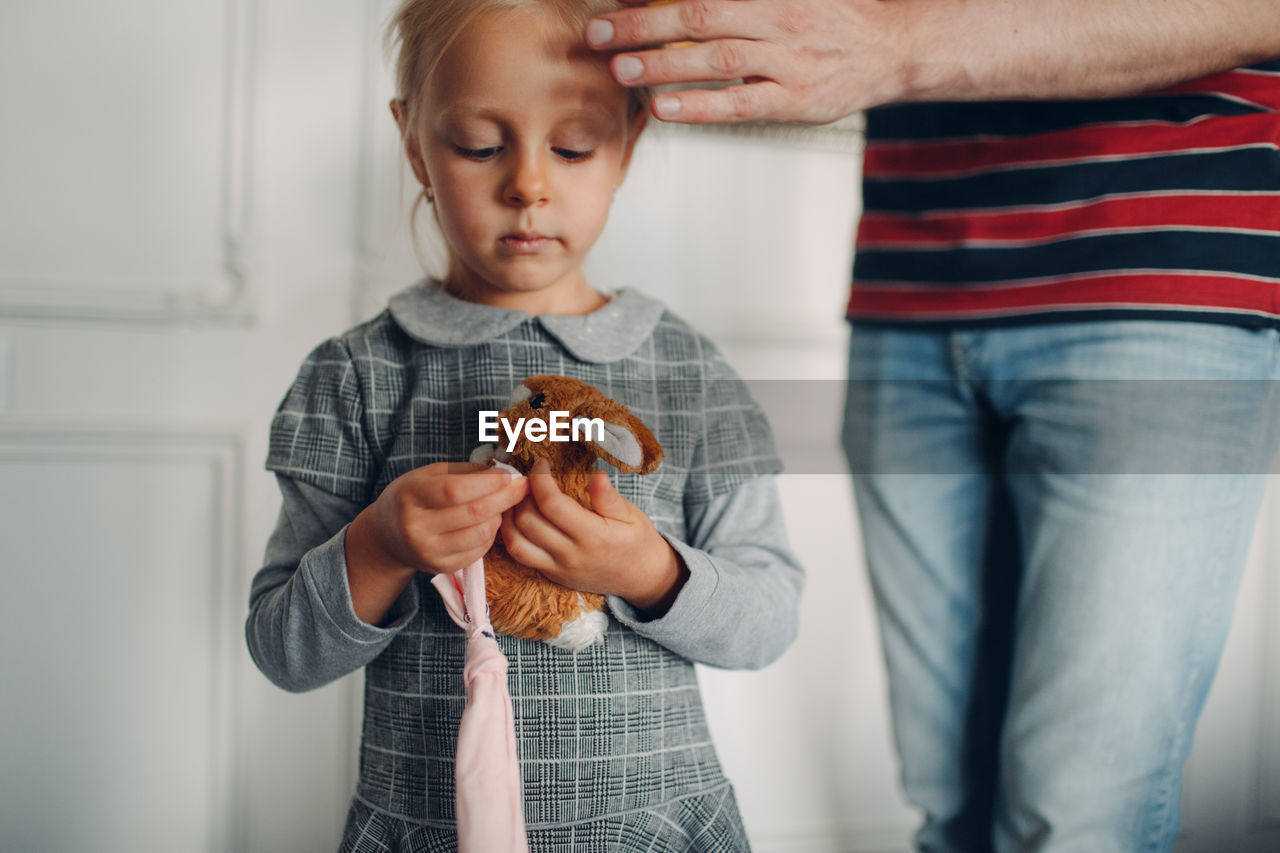 Midsection of father with daughter standing against wall