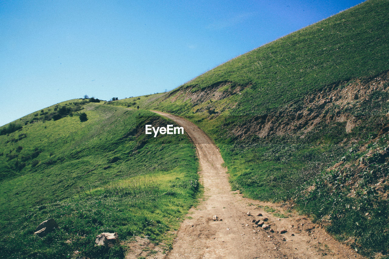 Empty footpath on mountains against clear blue sky