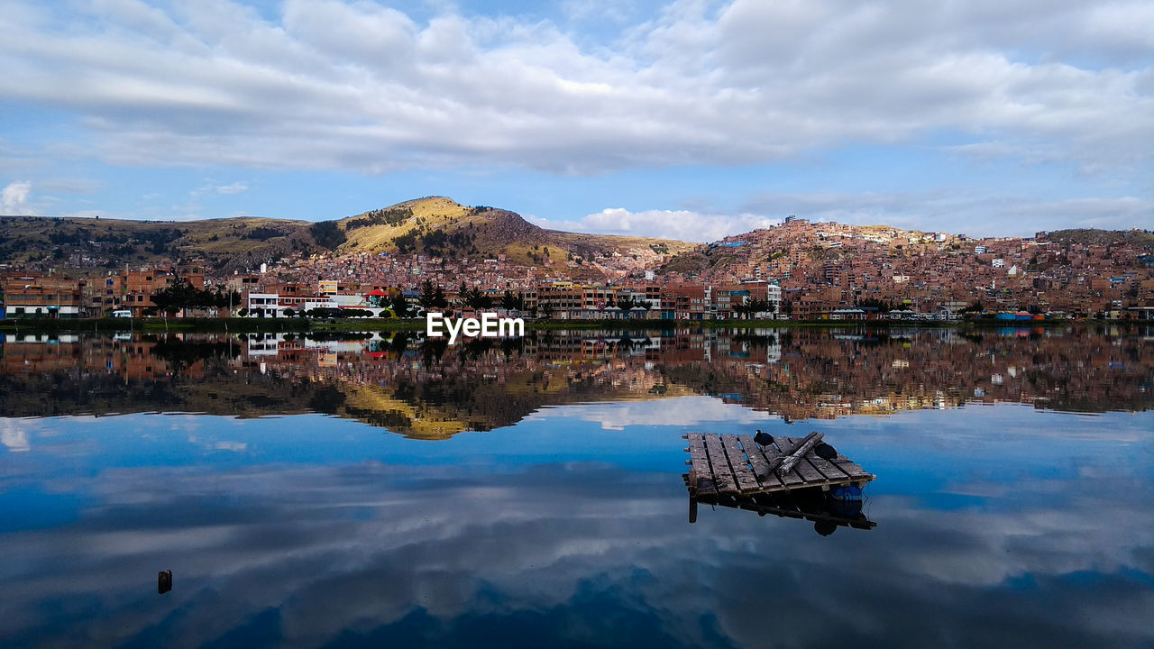 Scenic view of lake by buildings against sky