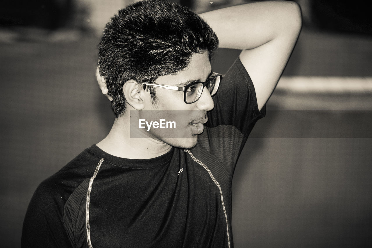 Young man wearing eyeglasses while looking away at playground