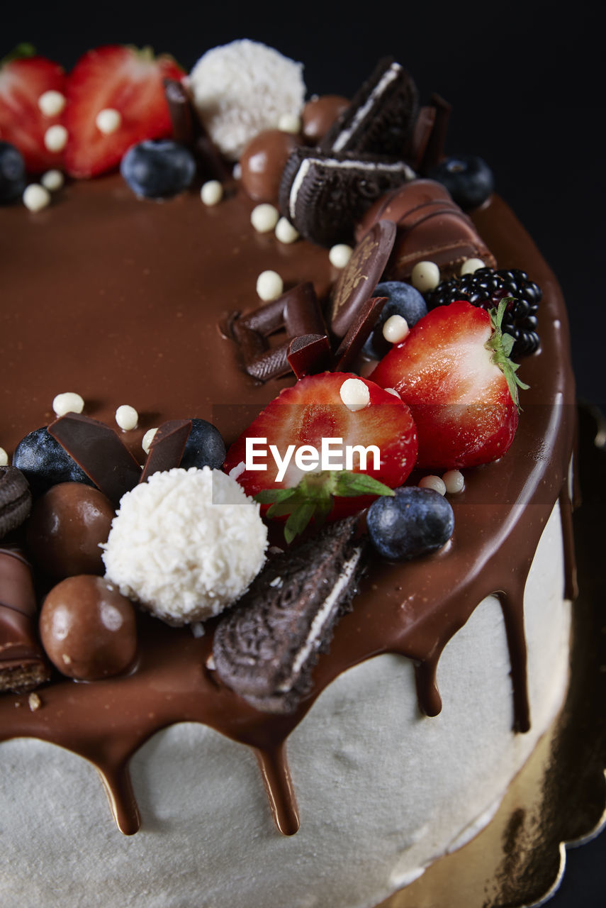 Cake decorated with strawberry and chocolate on dark background