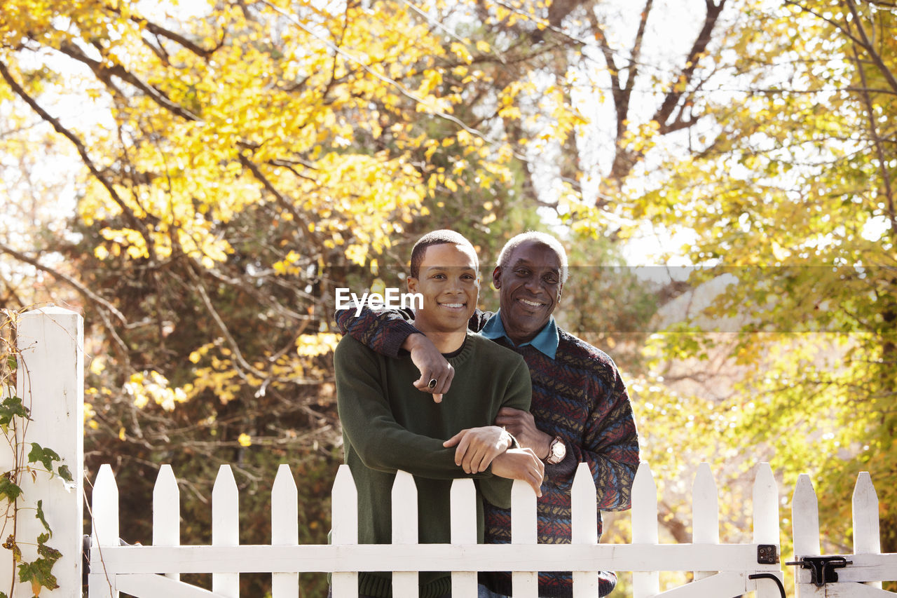 Portrait of father and son standing by fence