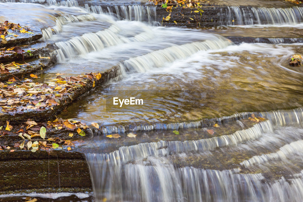Waterfall with autumn leaves on slated stone in in the creek