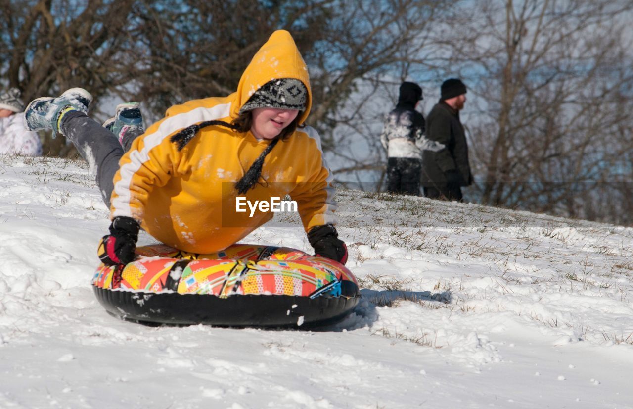 Smiling woman sliding on snow covered field