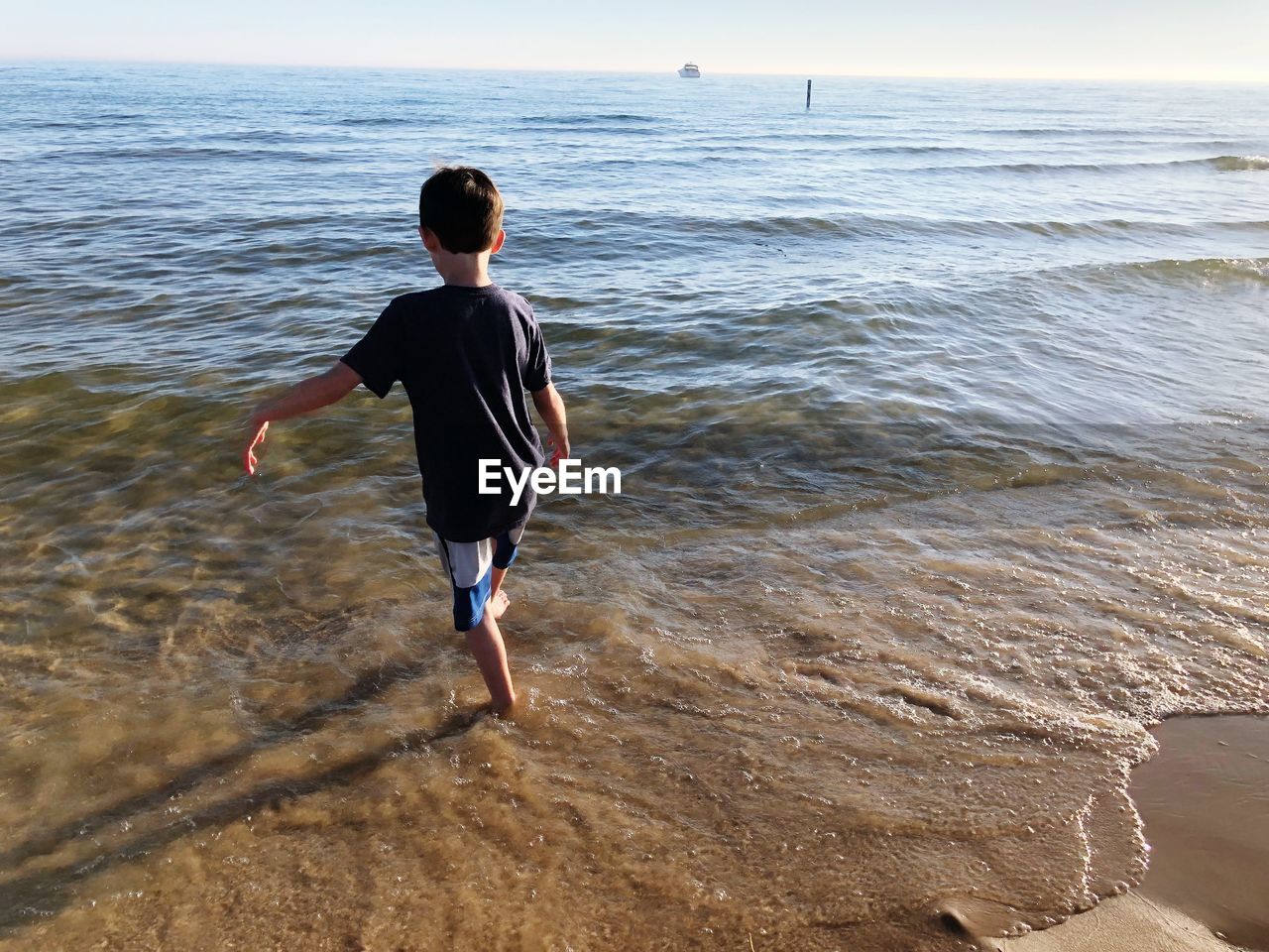 FULL LENGTH REAR VIEW OF SHIRTLESS MAN AT BEACH