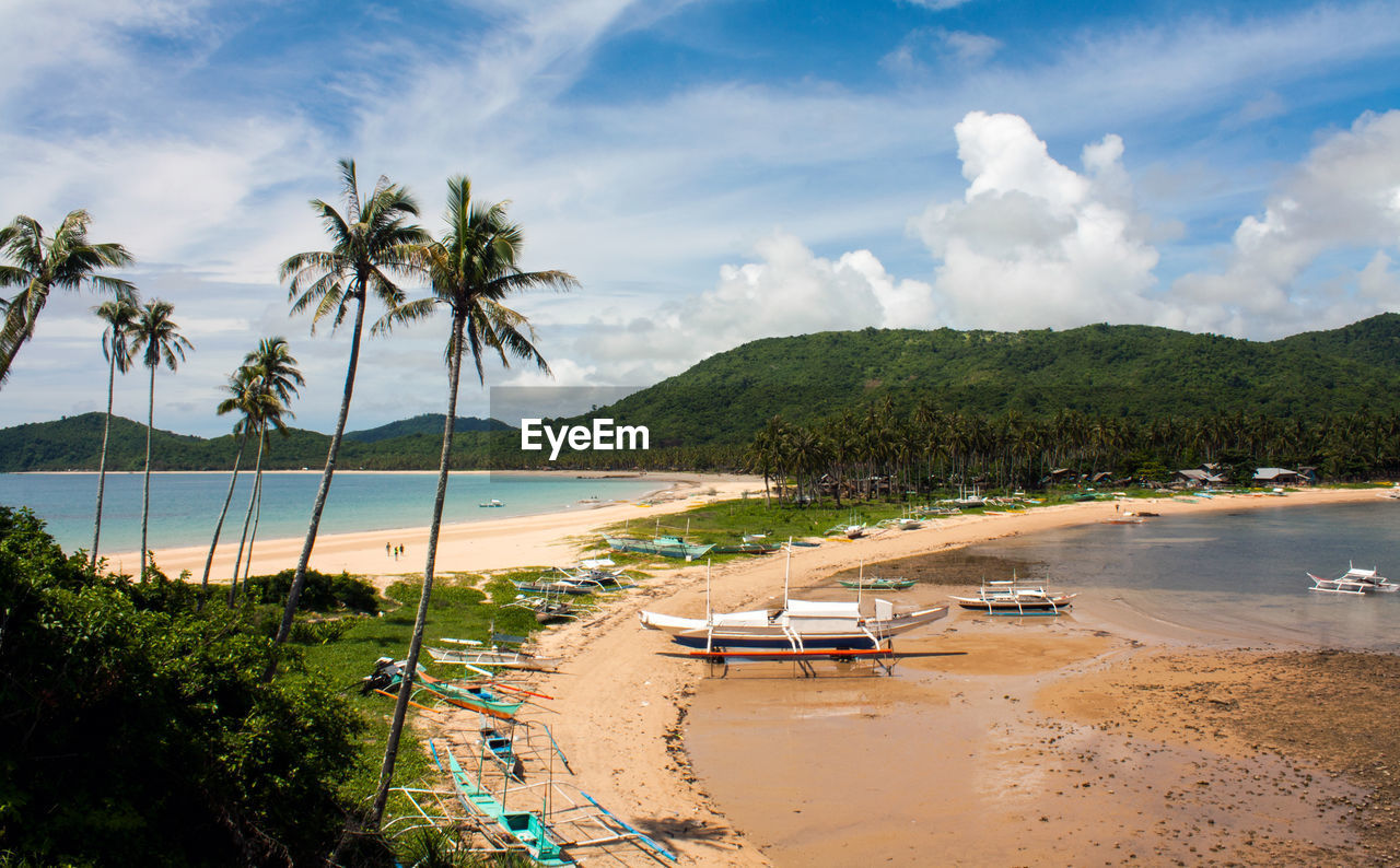 Outrigger boats moored at beach against sky