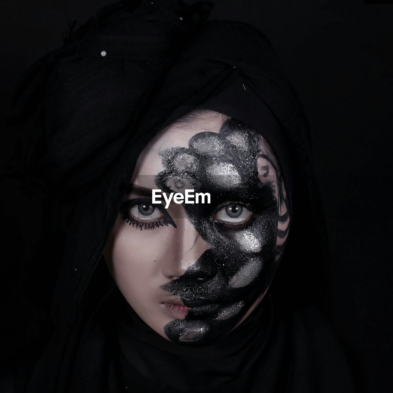 Portrait of fashion model with glitter face paint against black background