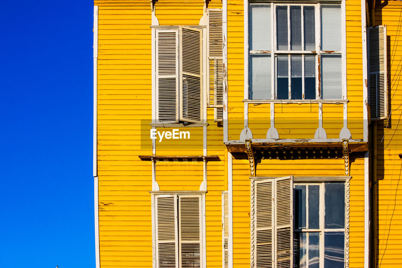 LOW ANGLE VIEW OF YELLOW BUILDING AGAINST CLEAR BLUE SKY