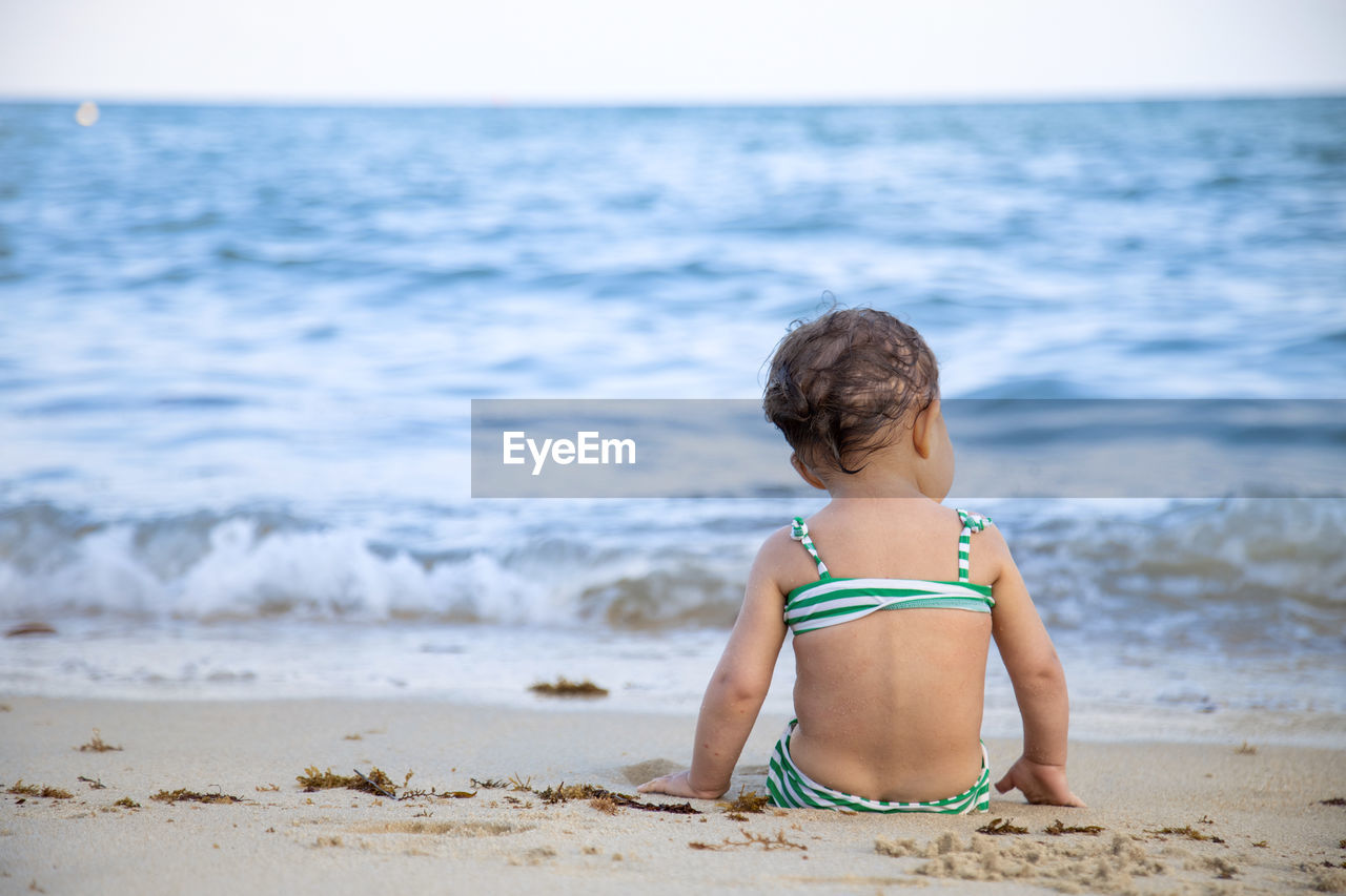 Rear view of girl sitting on beach