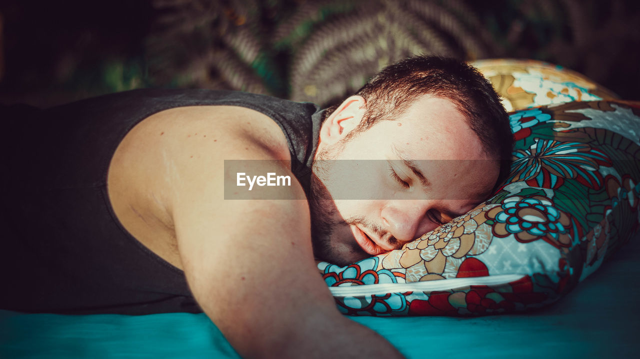 Portrait of young man sleeping on bed in the woods.