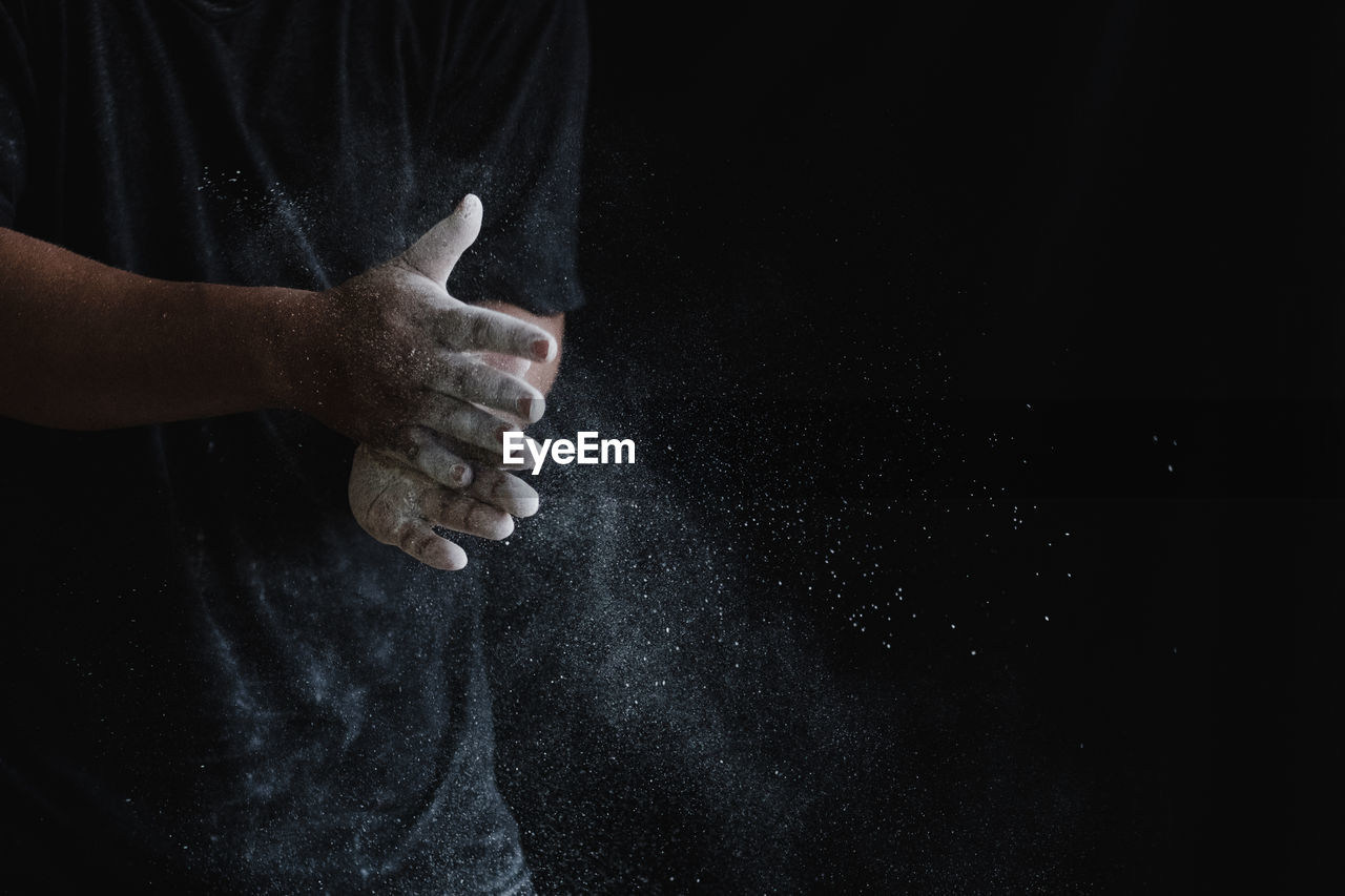 CLOSE-UP OF PERSON HAND HOLDING BLACK BACKGROUND