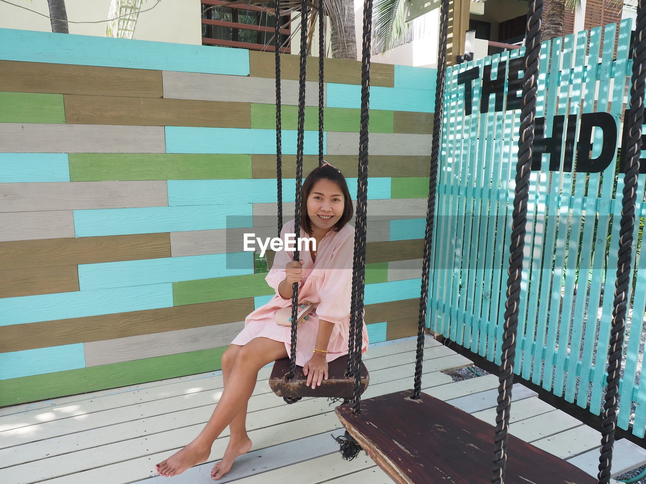 Portrait of smiling young woman sitting on swing