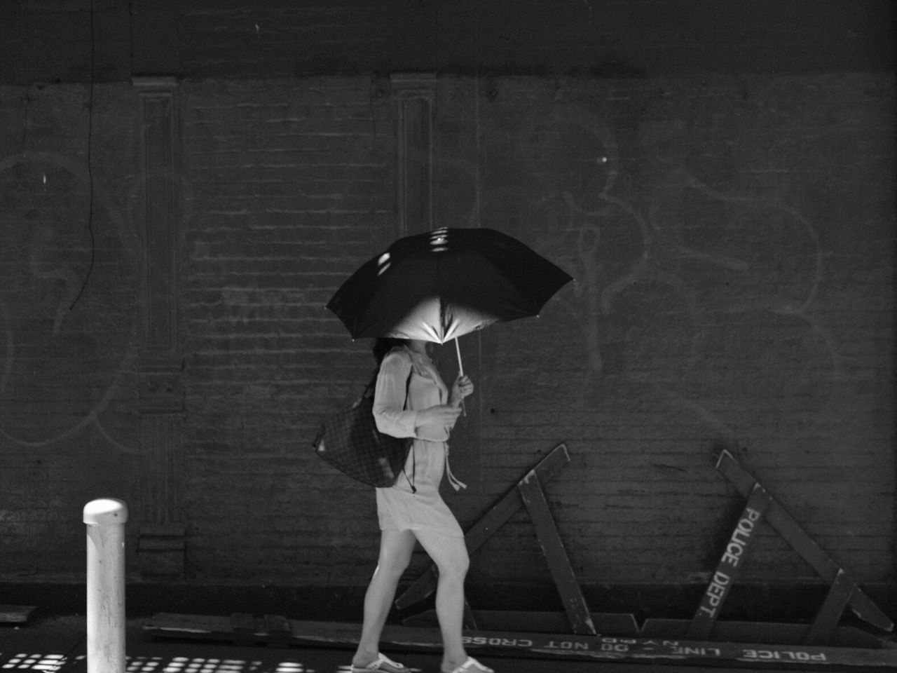 Woman walking with umbrella against wall