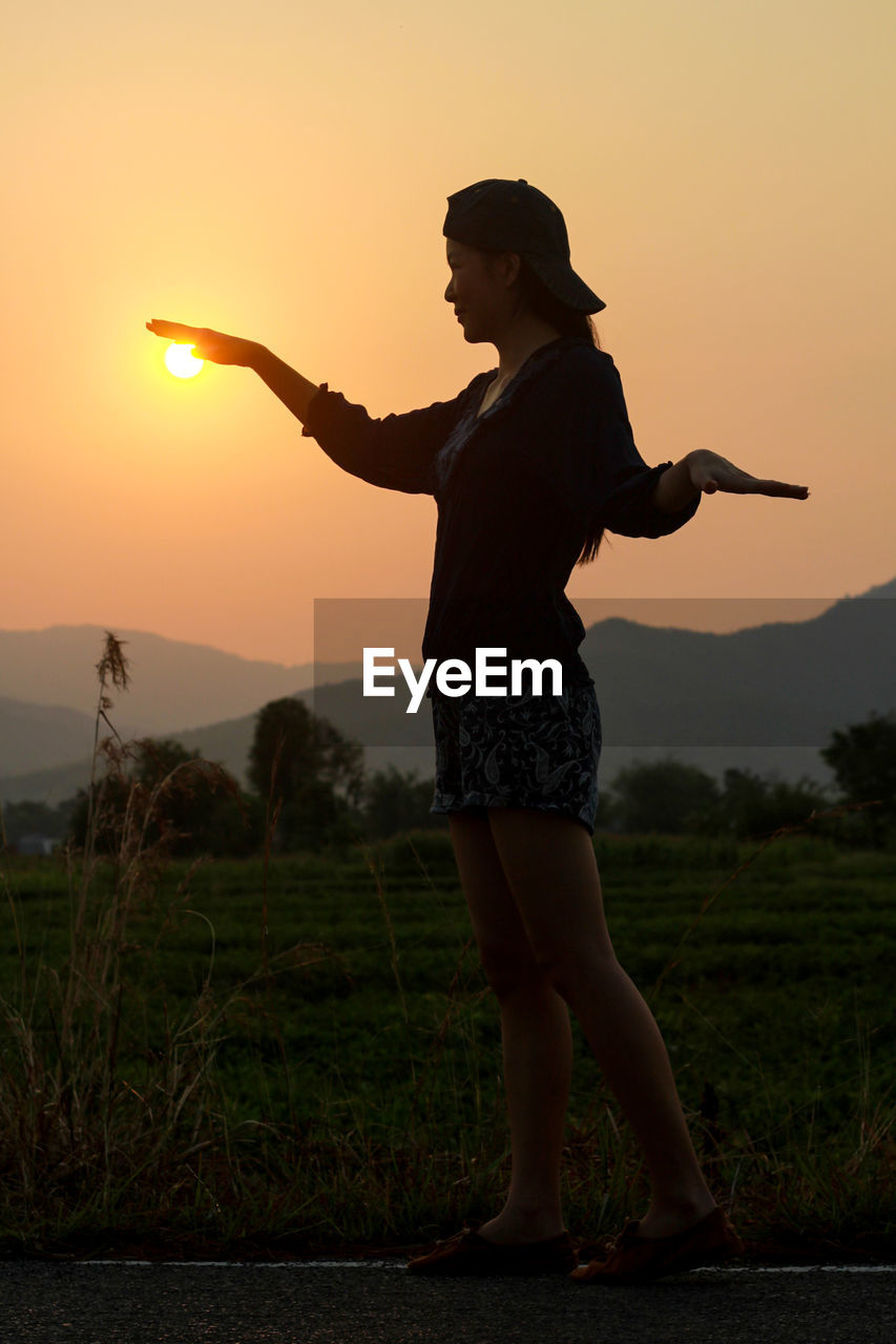 Full length of silhouette woman walking on road against sky during sunset