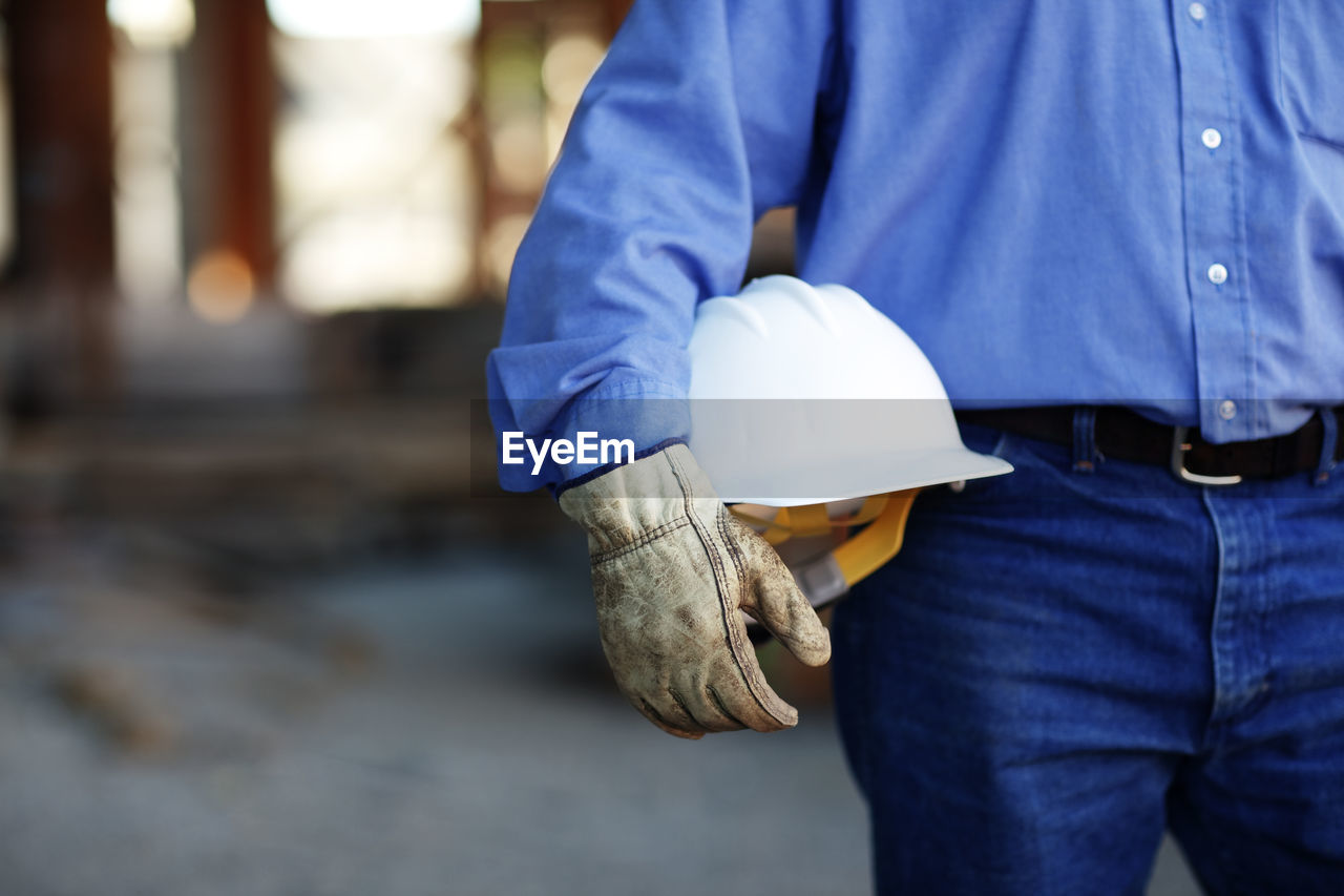 Close up of a male construction foreman worker holding a hard ha