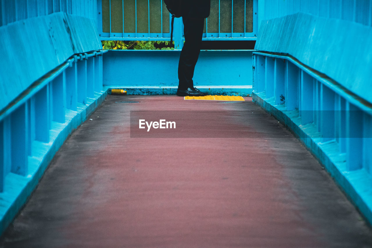 Low section of man standing on pedestrian bridge