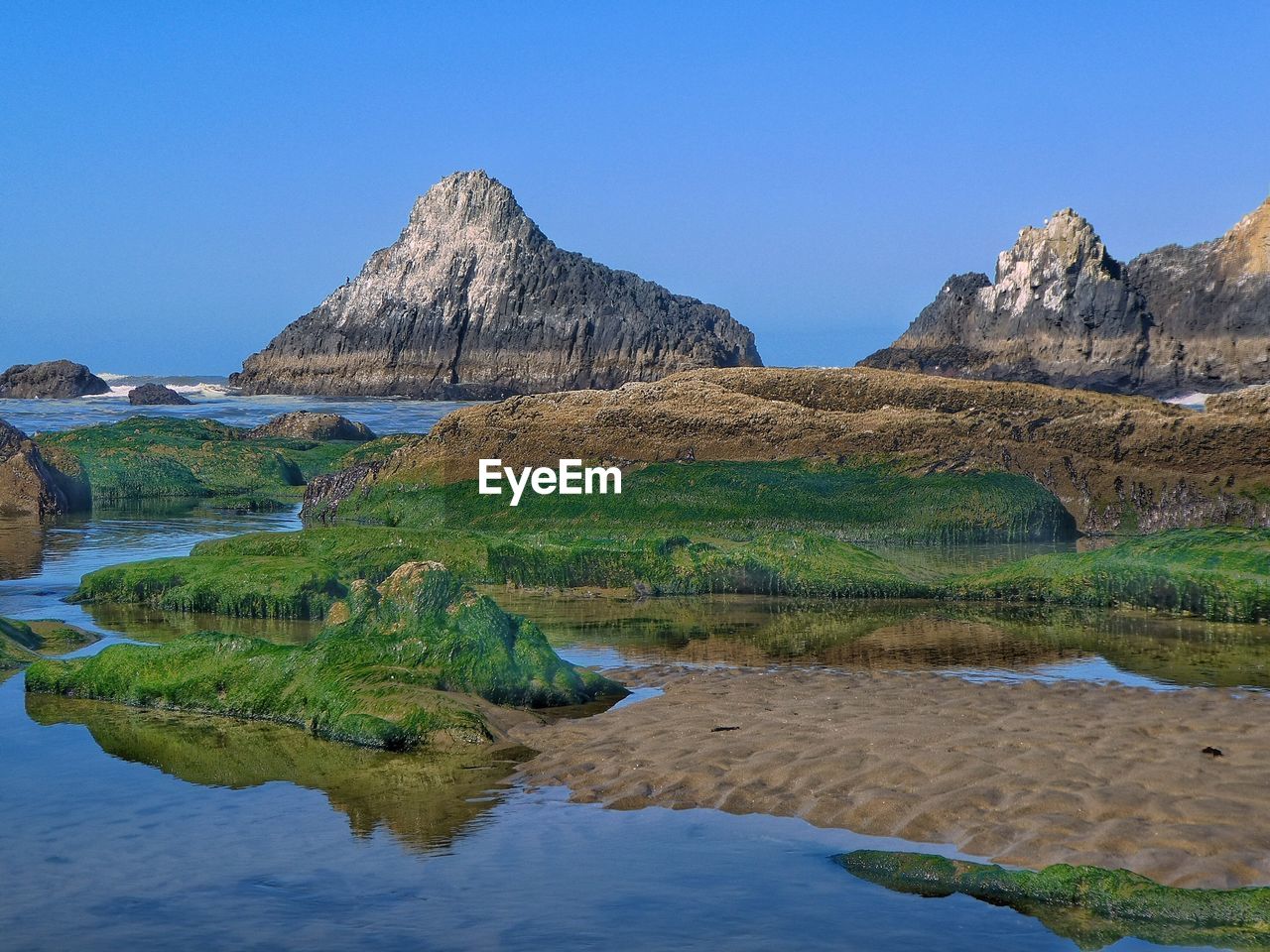 Scenic view of rocks in water against clear blue sky