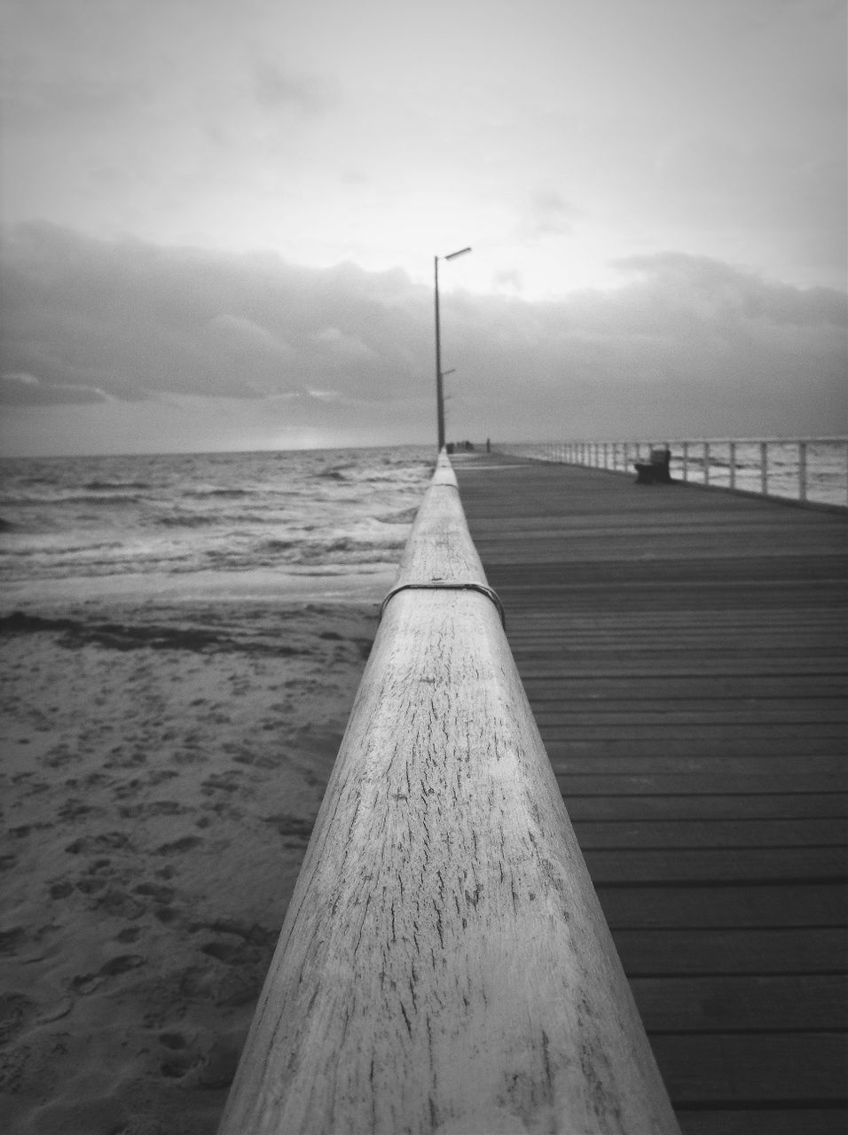 Close-up of wooden railing of pier on beach against sky