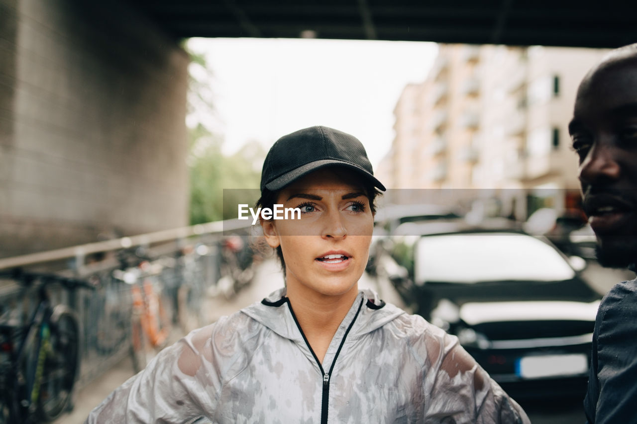 Female athlete talking with sportsman while standing on sidewalk in city