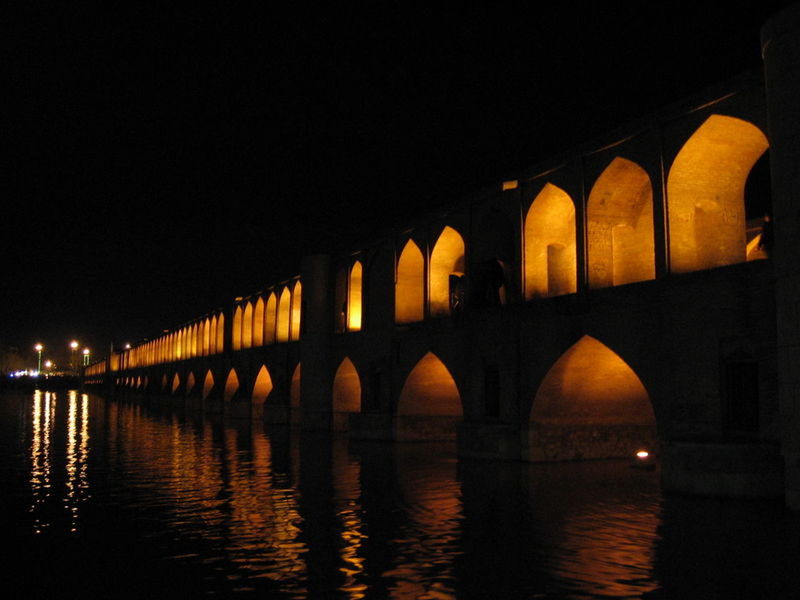 ILLUMINATED BRIDGE OVER RIVER AT NIGHT