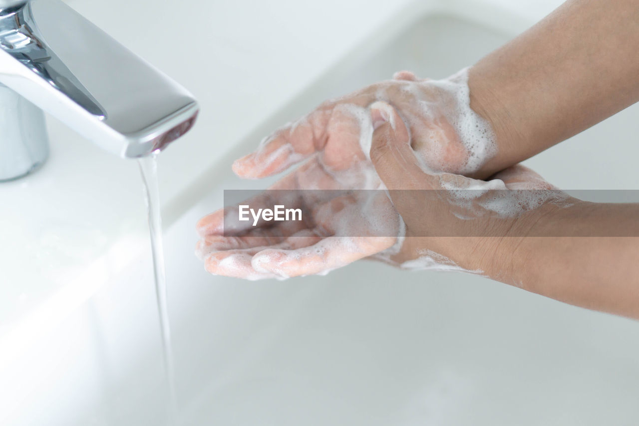 Cropped image of person washing hands in bathroom sink