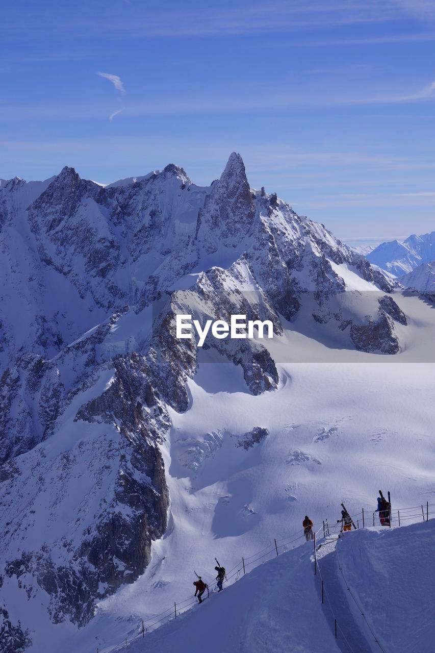 PEOPLE ON SNOWCAPPED MOUNTAINS AGAINST SKY