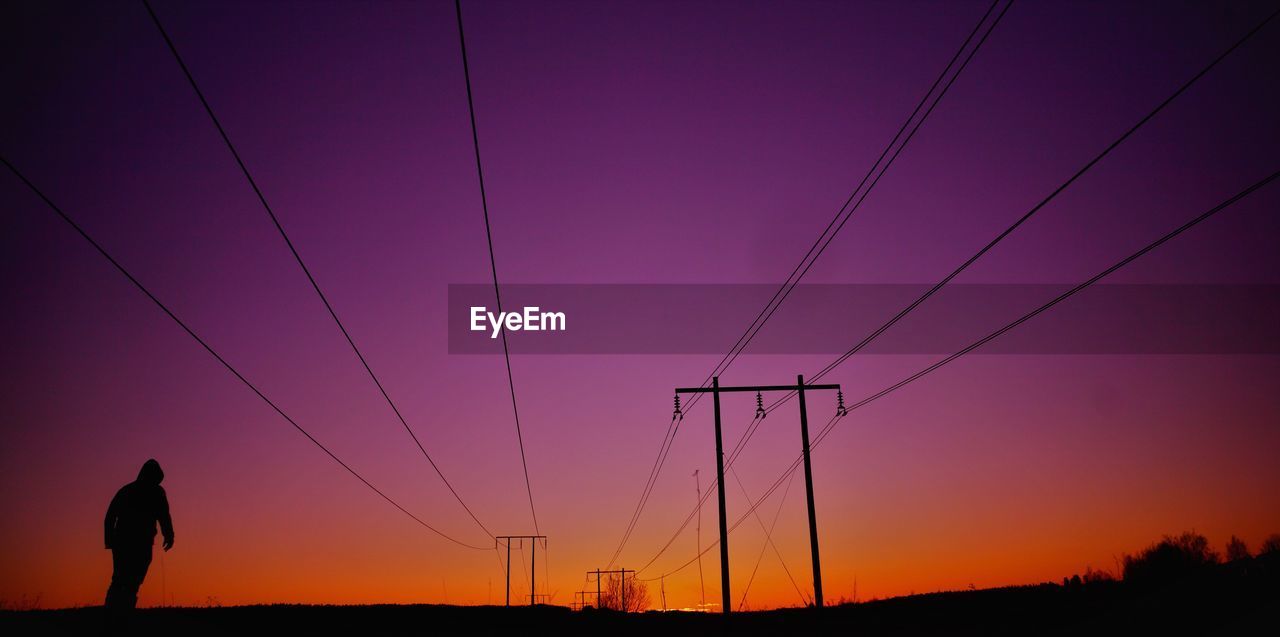 Silhouette of an by electricity pylon against sky during sunset