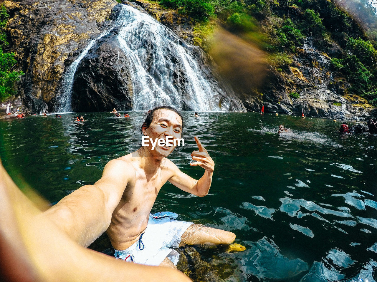 Full length of shirtless man standing on rock