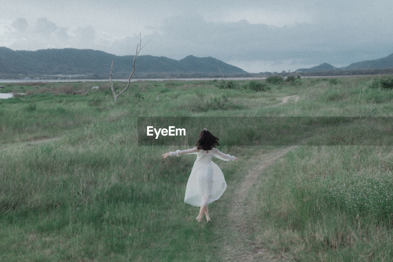 REAR VIEW OF WOMAN WALKING ON LANDSCAPE