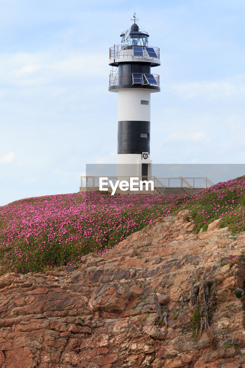 Low angle view of lighthouse by building against sky