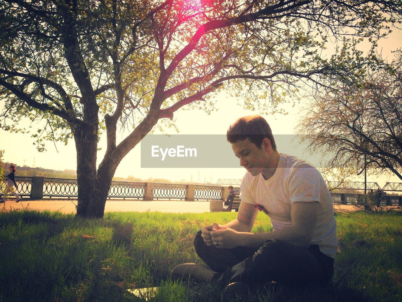 MAN SITTING ON TREE AGAINST SKY