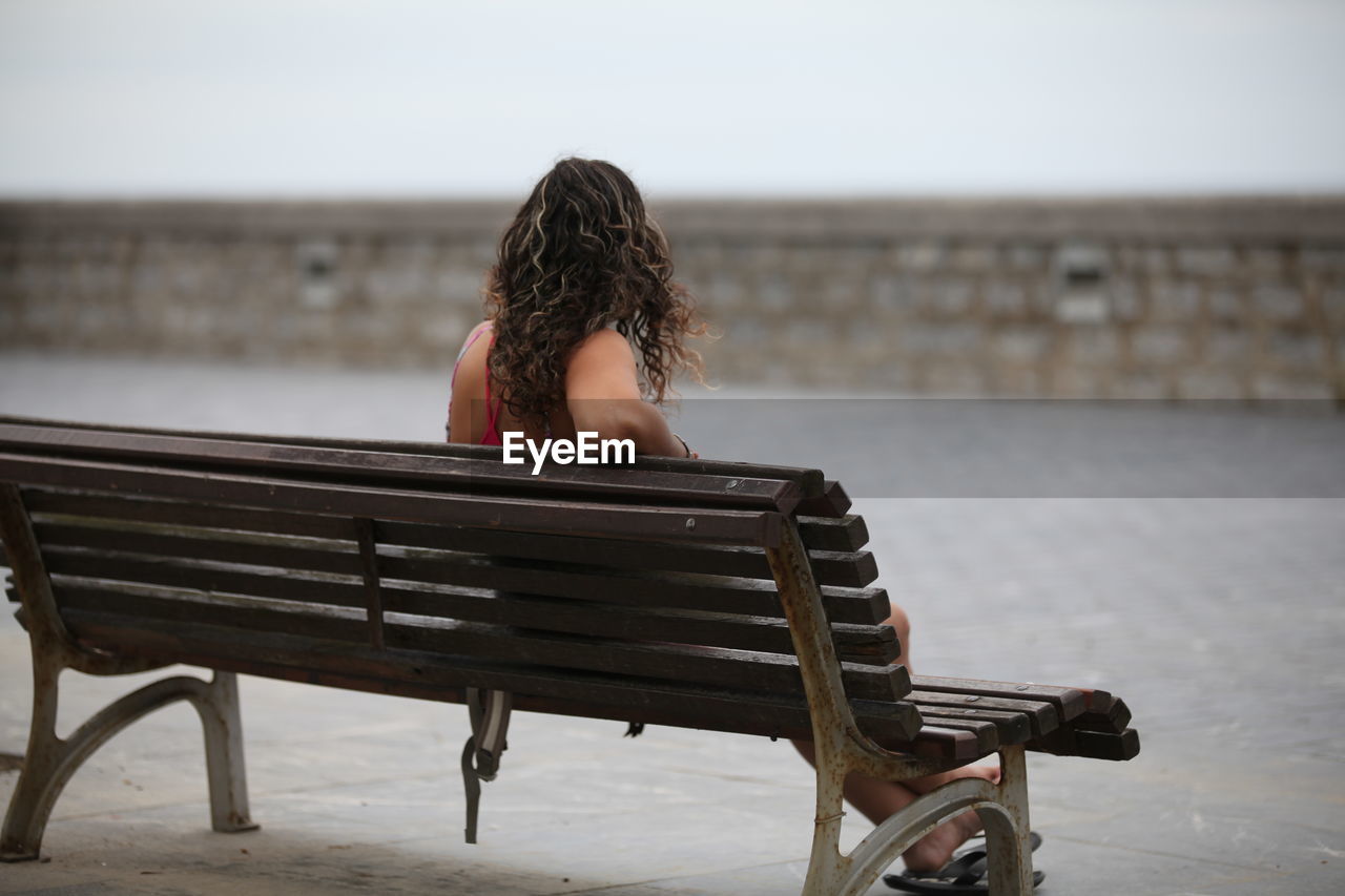 Rear view of woman sitting on bench