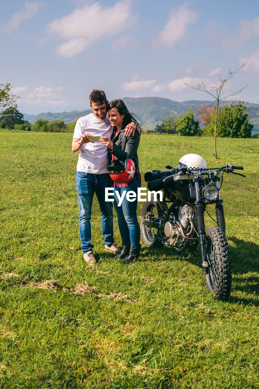 Young couple taking selfie against sky