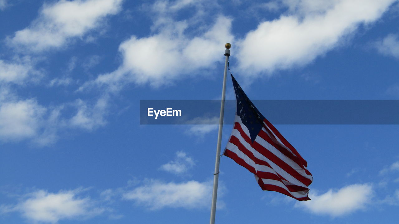 Low angle view of american flag against cloudy sky