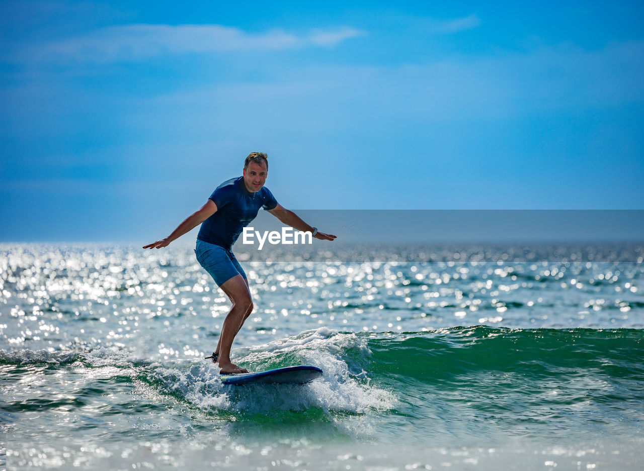 full length of young woman jumping in sea against sky