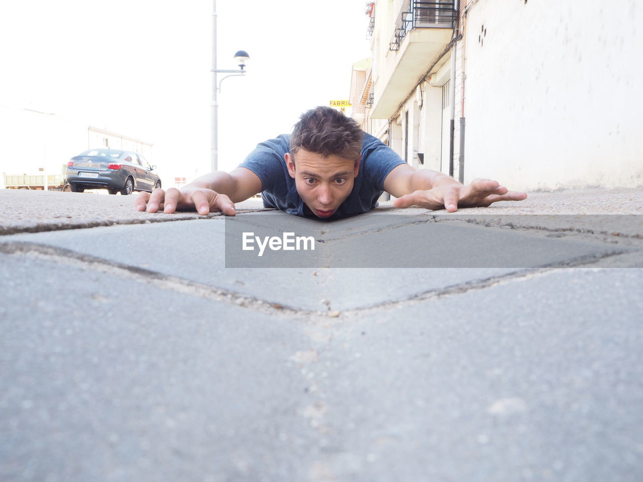 Surprised man lying down on street in city