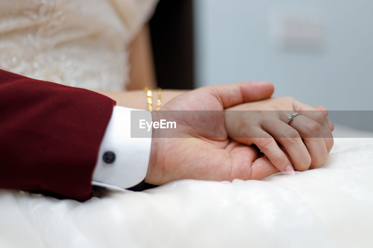 Cropped image of bridegroom holding bride hand