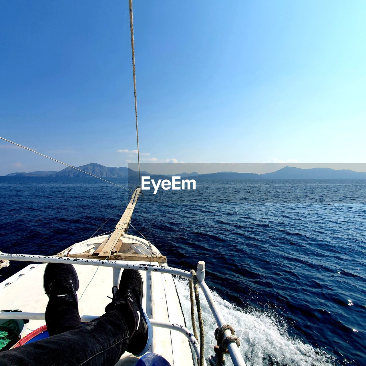 LOW SECTION OF MAN SAILING ON SEA AGAINST SKY