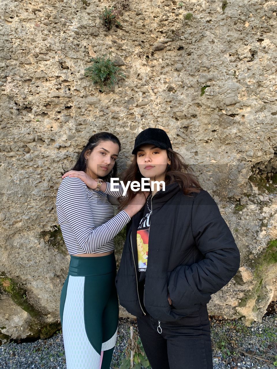 Portrait of smiling young women standing against rock formation