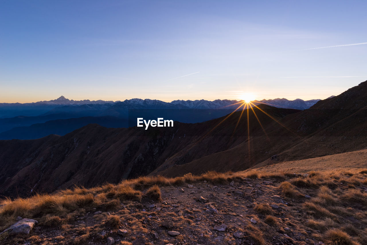 Surface level of barren landscape against clear blue sky