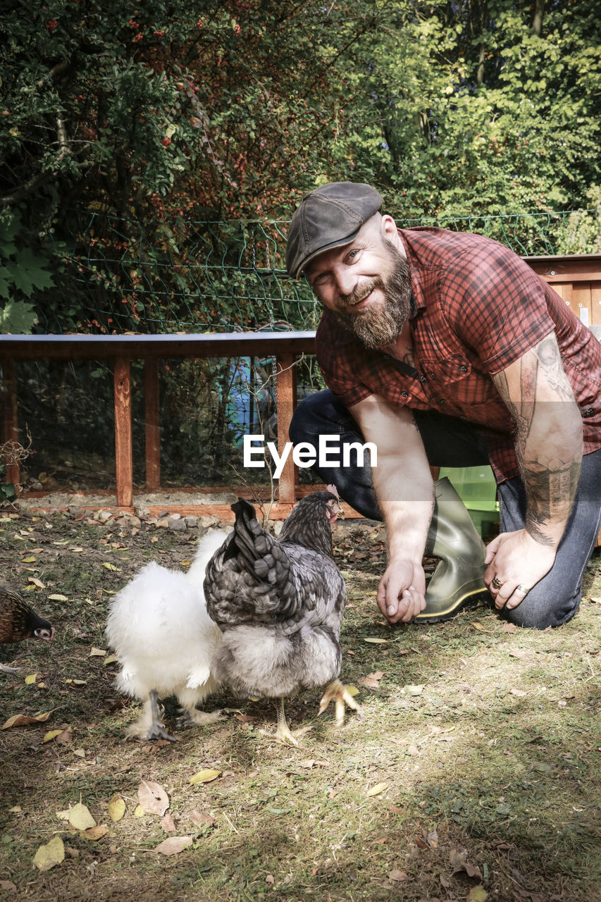 Man in his own garden, man feeding free range chickens