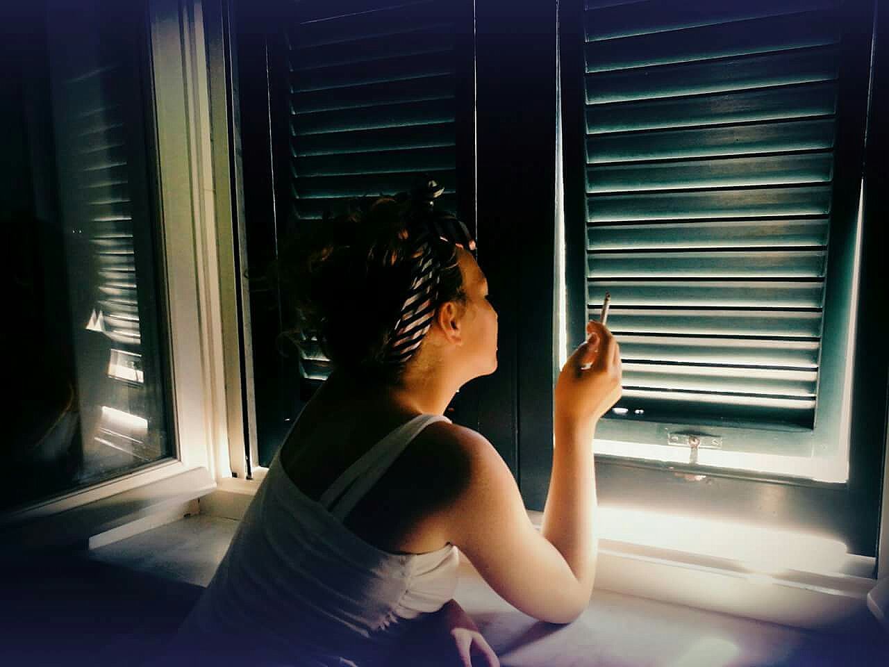 Woman smoking cigarette by closed window