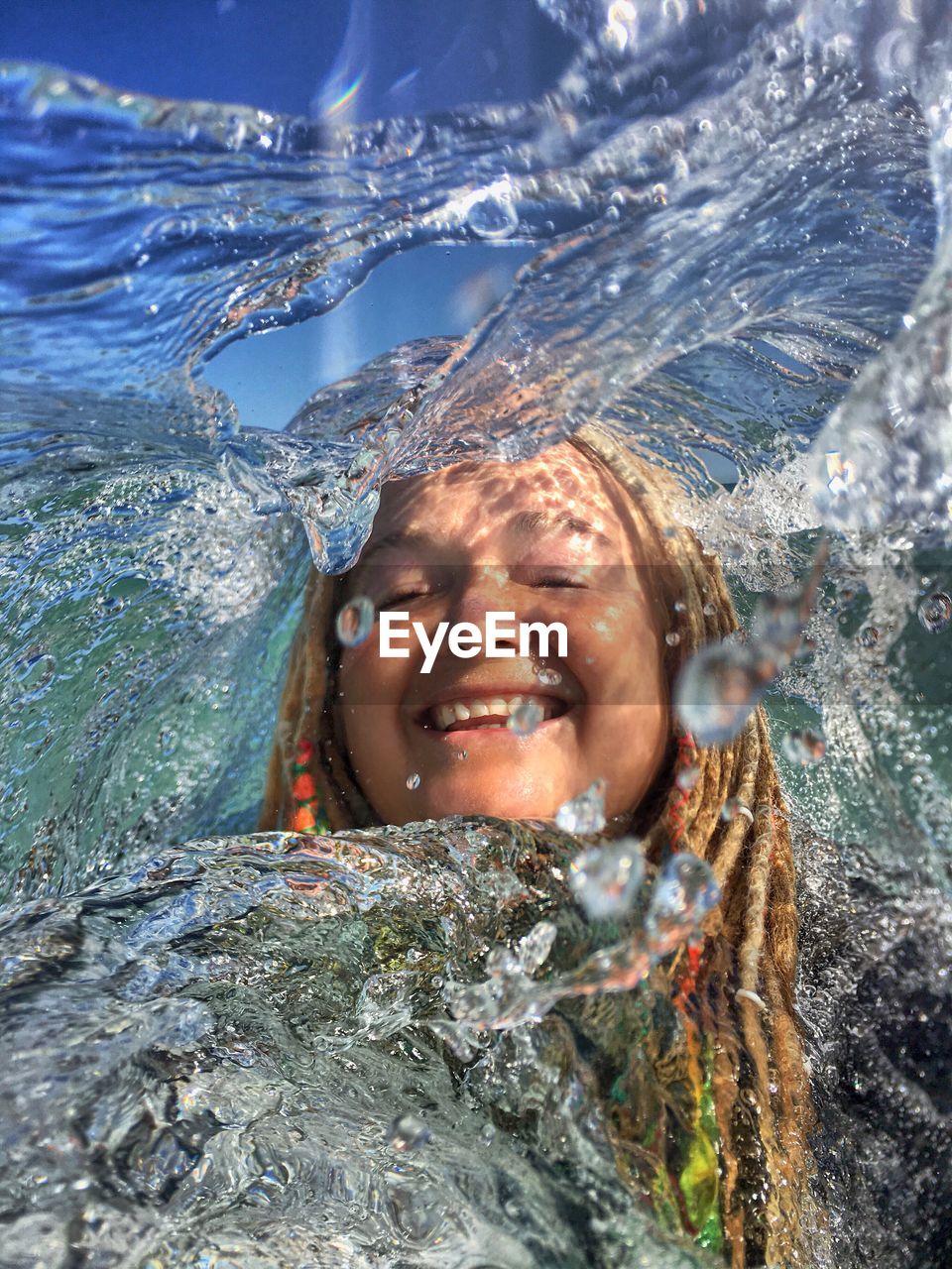 Portrait of smiling young woman swimming in water