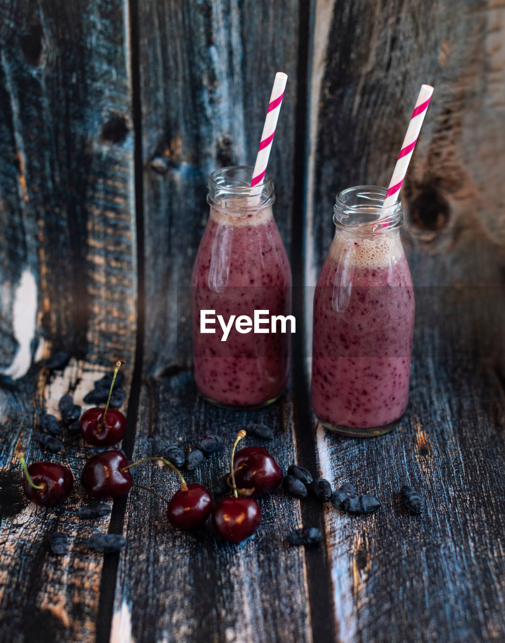 Homemade smoothie of fresh summer berries in glass bottles with paper tubes. 
