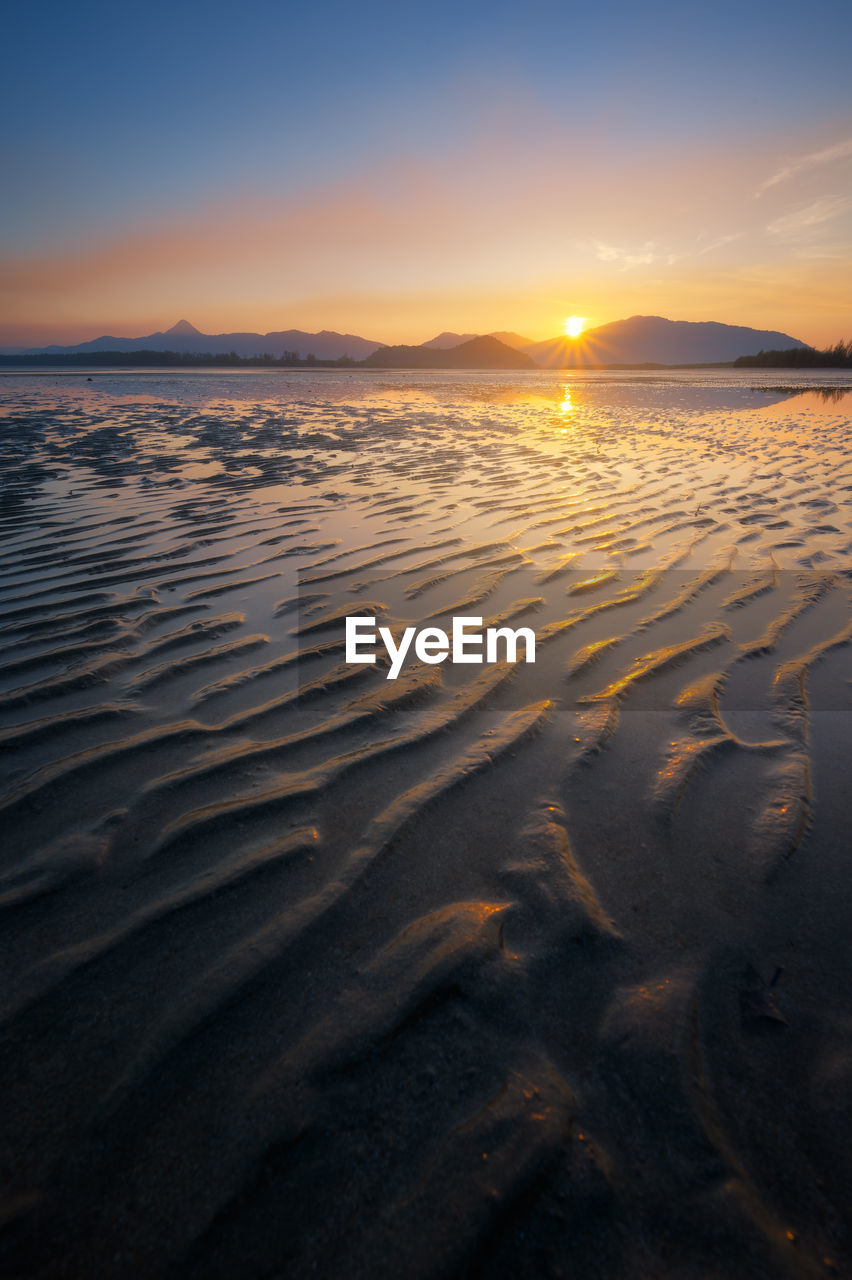 SCENIC VIEW OF BEACH AGAINST SKY AT SUNSET