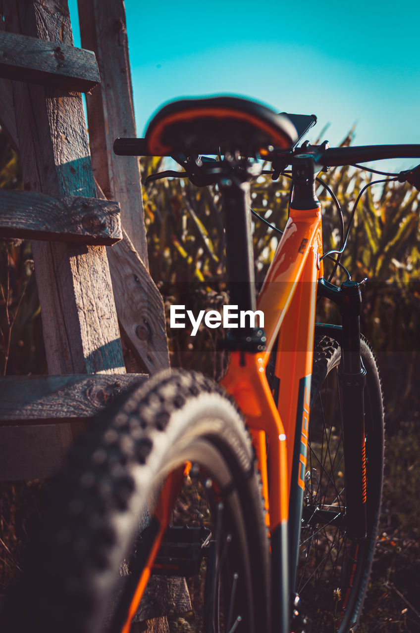 Portrait shot of the backside of an orange mountain bike against a corn field in autumn